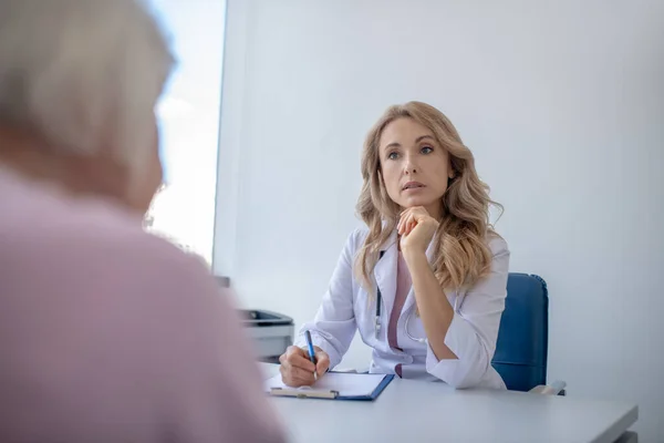 Blond läkare lyssnar noga på patienten — Stockfoto