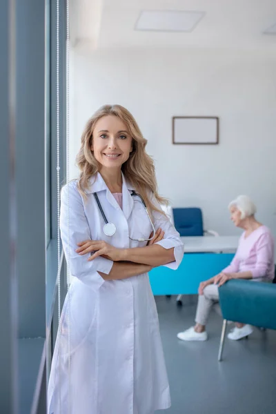 Довгошерста блондинка лікар стоїть з схрещеними руками — стокове фото