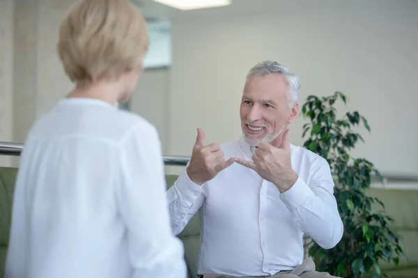 Barbudo hombre de pelo gris hablando con mujer rubia usando lenguaje de señas — Foto de Stock