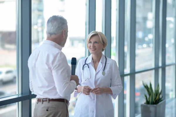 Giornalista maschio dai capelli grigi intervistando medico donna bionda — Foto Stock