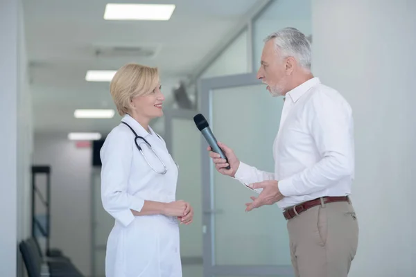 Gråhårig manlig journalist med intervju med leende blond kvinnlig läkare i Corrido — Stockfoto