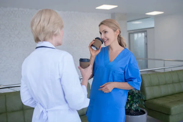 Two female doctors enjoying coffee, laughing, talking