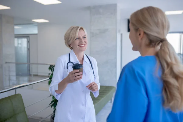 Duas médicas gostando de café, tendo uma conversa amigável — Fotografia de Stock