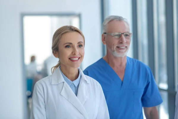 Sorridente medici maschili e femminili in piedi nel corridoio dell'ospedale — Foto Stock