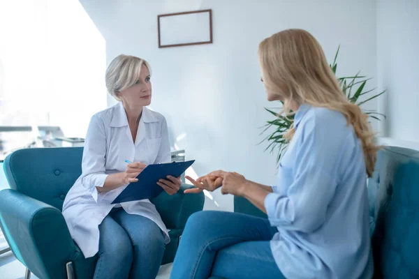 Blond kvinnlig läkare antecknar, konsultera kvinnlig patient — Stockfoto
