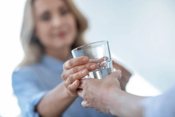 Primer plano de las manos femeninas dando vaso de agua a la hembra rubia —  Fotos de Stock