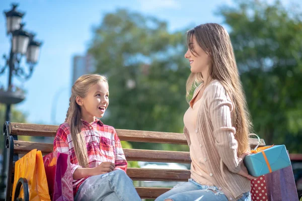 Mutter präsentiert ihre süße Tochter-Geschenkbox auf Parkbank — Stockfoto