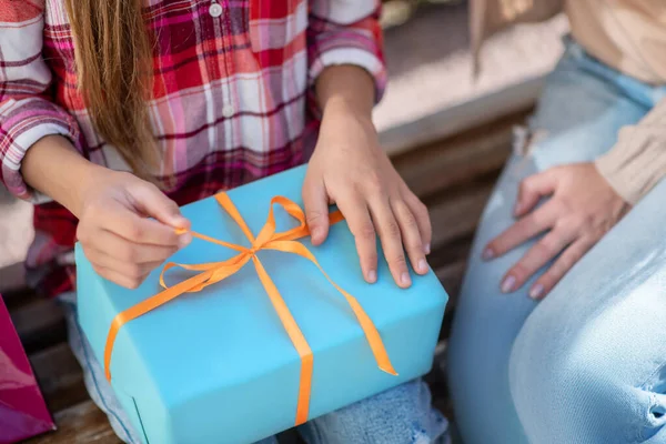 Close-up of girl hands opening present box on park bench — Stock Photo, Image