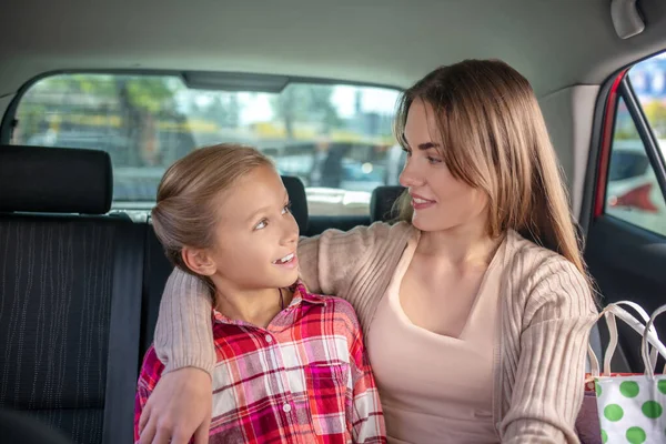 Mutlu anne arabasının arka koltuğunda kızına sarılıyor. — Stok fotoğraf