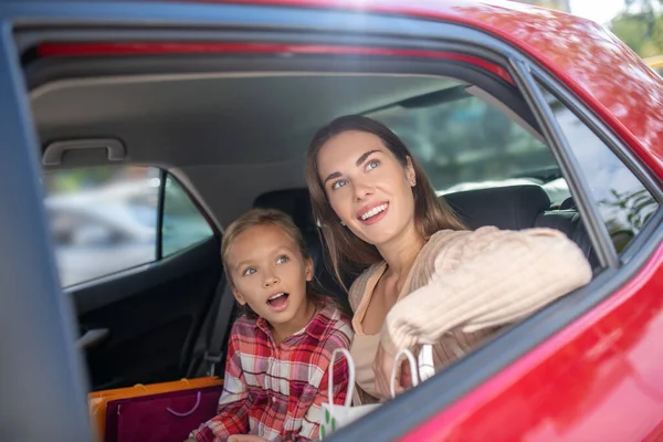 Şaşırmış kız ve annesi arabanın arka koltuğunda pencereden dışarı bakıyorlar. — Stok fotoğraf