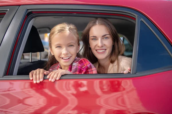 Mutlu kız ve annesi arabanın arka koltuğunda pencereden dışarı bakıyorlar. — Stok fotoğraf