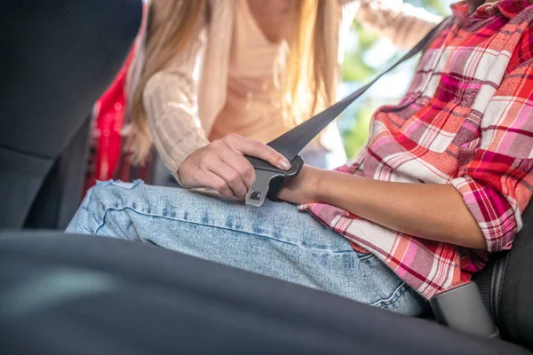 Primer plano de las manos femeninas que sujetan el cinturón de seguridad de las niñas en el asiento trasero del coche —  Fotos de Stock