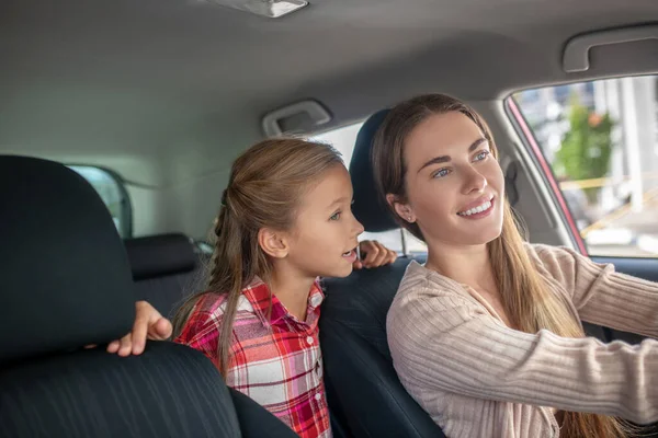 Mutlu kız, arabanın arka koltuğundan annesiyle konuşuyor. — Stok fotoğraf