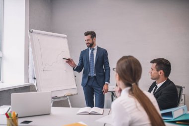 Gülümseyen adam iki meslektaşını işaret ediyor.