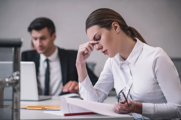 Femme de profil étudiant un document assis au bureau — Photo