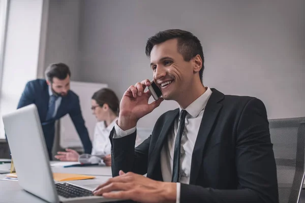 オフィスでスマートフォンで話している笑顔ビジネスマン — ストック写真