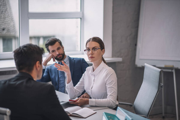 Successful woman with glasses talking with man sitting back