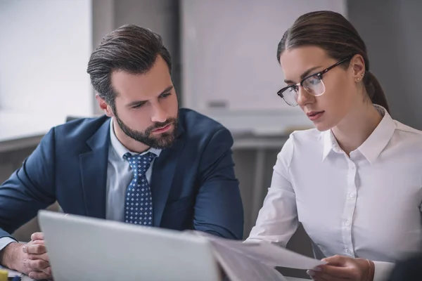 Homme et femme barbus dans des lunettes regardant des documents — Photo