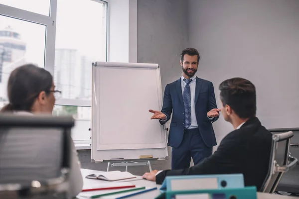 Sonriente hombre barbudo hablando y dos colegas — Foto de Stock