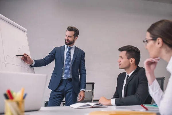 Succesvolle man toont grafiek op stand aan collega 's — Stockfoto