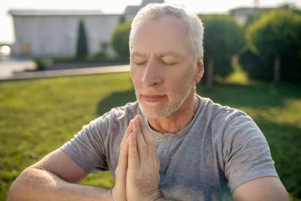 Starší šedovlasý samec meditující venku, ruce v namaste — Stock fotografie