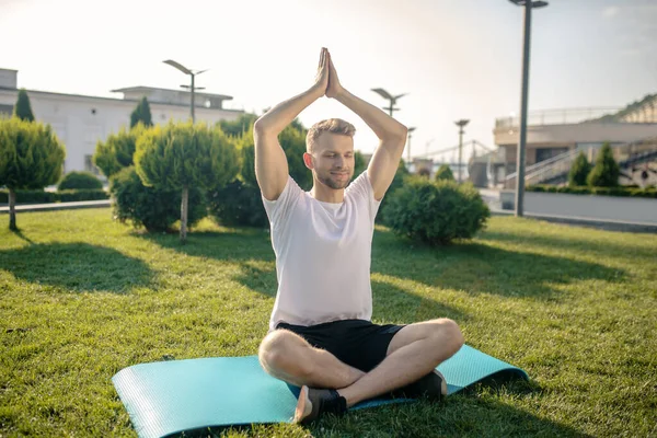 Joven barbudo practicando yoga al aire libre, levantando manos por encima de la cabeza — Foto de Stock