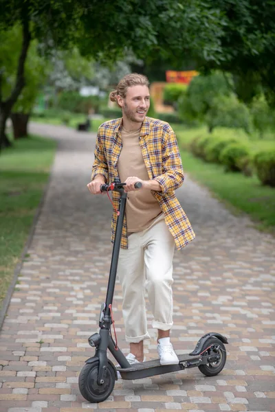 Young man riding a scooter in the park — Stock Photo, Image