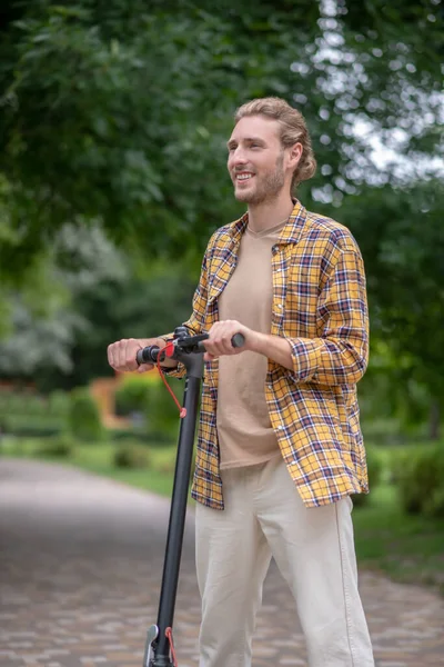 Young man with a scooter looking contented — Stock Photo, Image