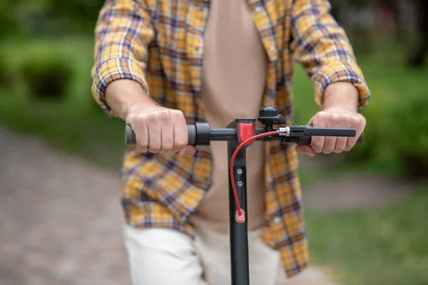 Photo d'un homme en chemise à carreaux chevauchant un scooter dans le parc — Photo