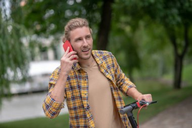 Motosikletli kareli bir adam telefonda konuşuyor.