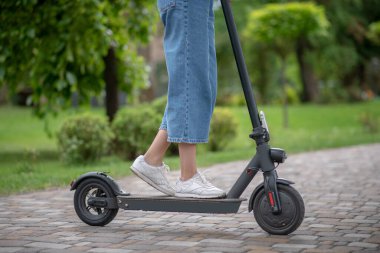 Scooter 'ın üzerinde duran kadın bacakları yakın plan.