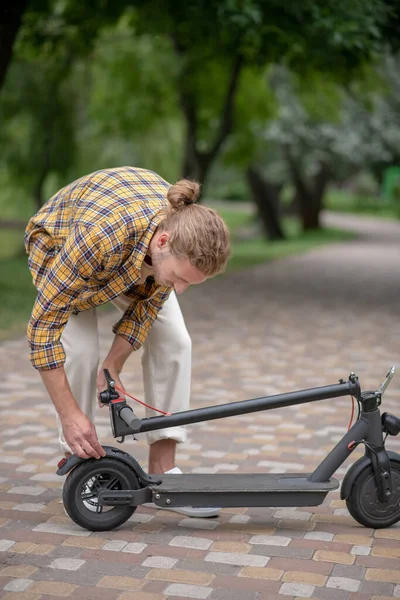 Homme en chemise à carreaux regardant occupé avec scooter push — Photo