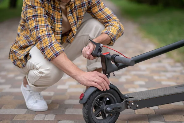 Homme assis sur ses bosseurs et fixer son scooter — Photo