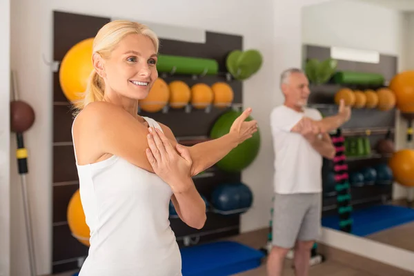 Bir adam ve bir kadın spor salonunda kollarını açıyorlar. — Stok fotoğraf