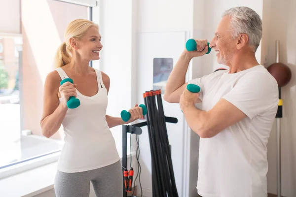 Šedovlasý vousatý muž ukazuje své biceps na ženu a pocit hrdosti — Stock fotografie