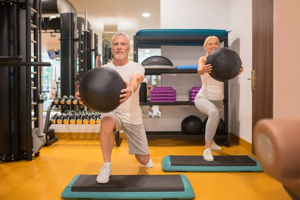 Um homem e uma mulher fazendo lunging com bolas — Fotografia de Stock