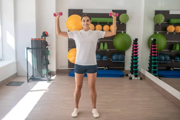 Koyu renk saçlı kadın spor salonunda dambıllarla çalışıyor. — Stok fotoğraf