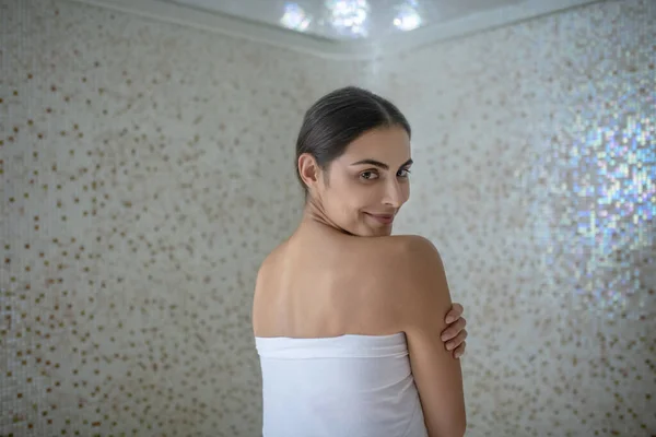 Rear view of dark-haired female wrapped in white towel — Stock Photo, Image