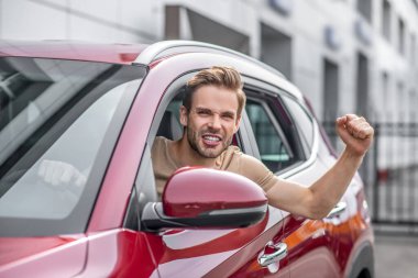 Heyecanlı erkek sürücü, havada el kaldırıyor.