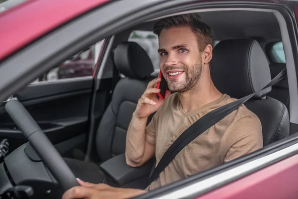 Uśmiechnięty młody mężczyzna prowadzi, rozmawia przez telefon — Zdjęcie stockowe