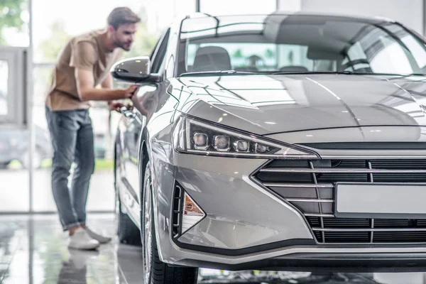 Muž zákazník zkoumá nové auto, ohýbání, nahlíží dovnitř — Stock fotografie