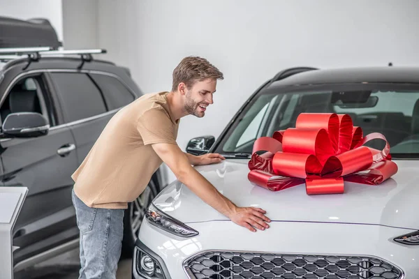 Hombre cliente poniendo sus manos capucha del coche con lazo rojo —  Fotos de Stock