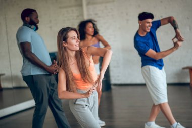 Bir grup insan dans dersinde yeni hareketler öğreniyor.