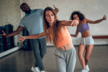 Grup arkadaşlarıyla hip-hop koreografisi öğrenen bir kadın.