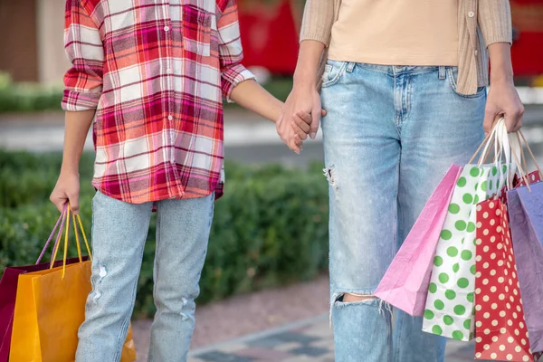 Zbliżenie nastolatki i kobiety spacerujących ręka w rękę z torbami na zakupy — Zdjęcie stockowe