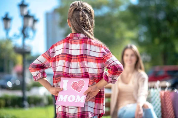 Вид сзади на девушку, держащую карту для мамы, сидящую на скамейке в парке — стоковое фото