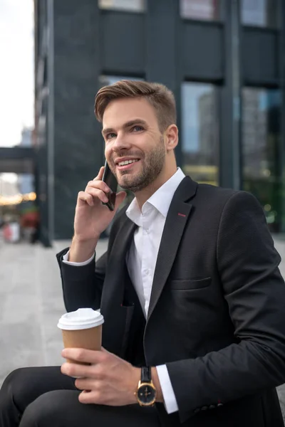 Елегантний чоловічий бізнесмен має каву і розмовляє по телефону — стокове фото