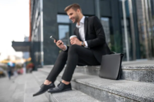 Elegante mannelijke zakenman die op de trap zit en sms 't — Stockfoto