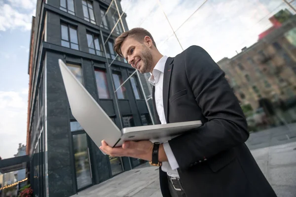 Mladý muž v černém obleku s laptopem v rukou — Stock fotografie