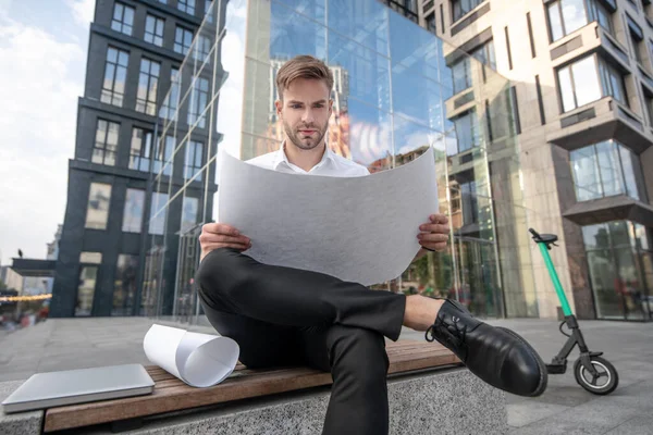 Hombre joven en camisa blanca mirando los materiales del proyecto — Foto de Stock